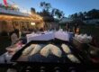 Family hibachi at home dinner with a child and adults seated around the grill during an evening backyard gathering