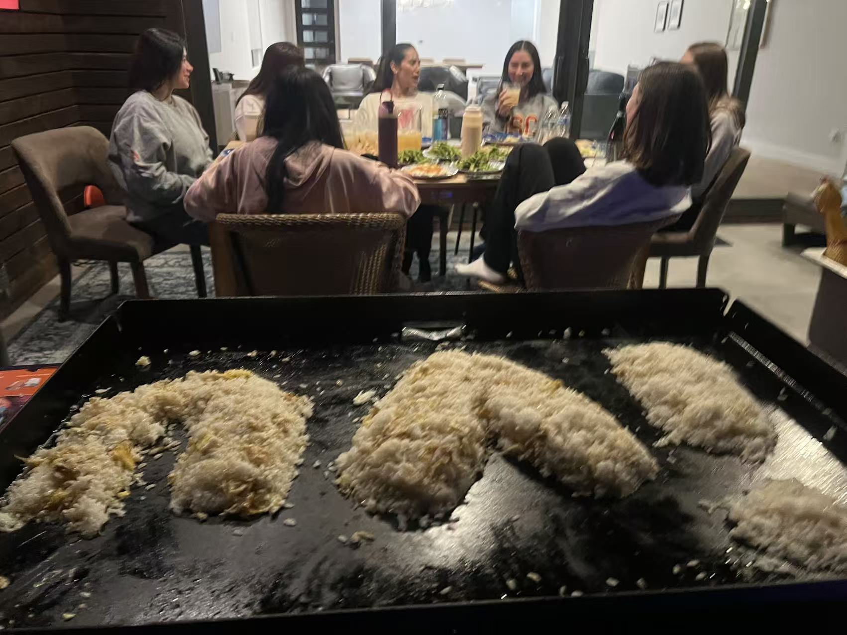 Family seated around an at-home hibachi grill with clear spacing for a private dinner party