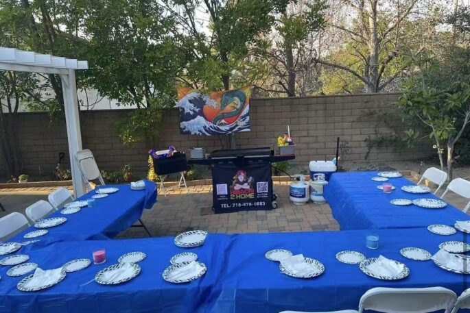 Hibachi 2 Home branded portable grill set up beside guest tables for a private backyard hibachi dinner at home