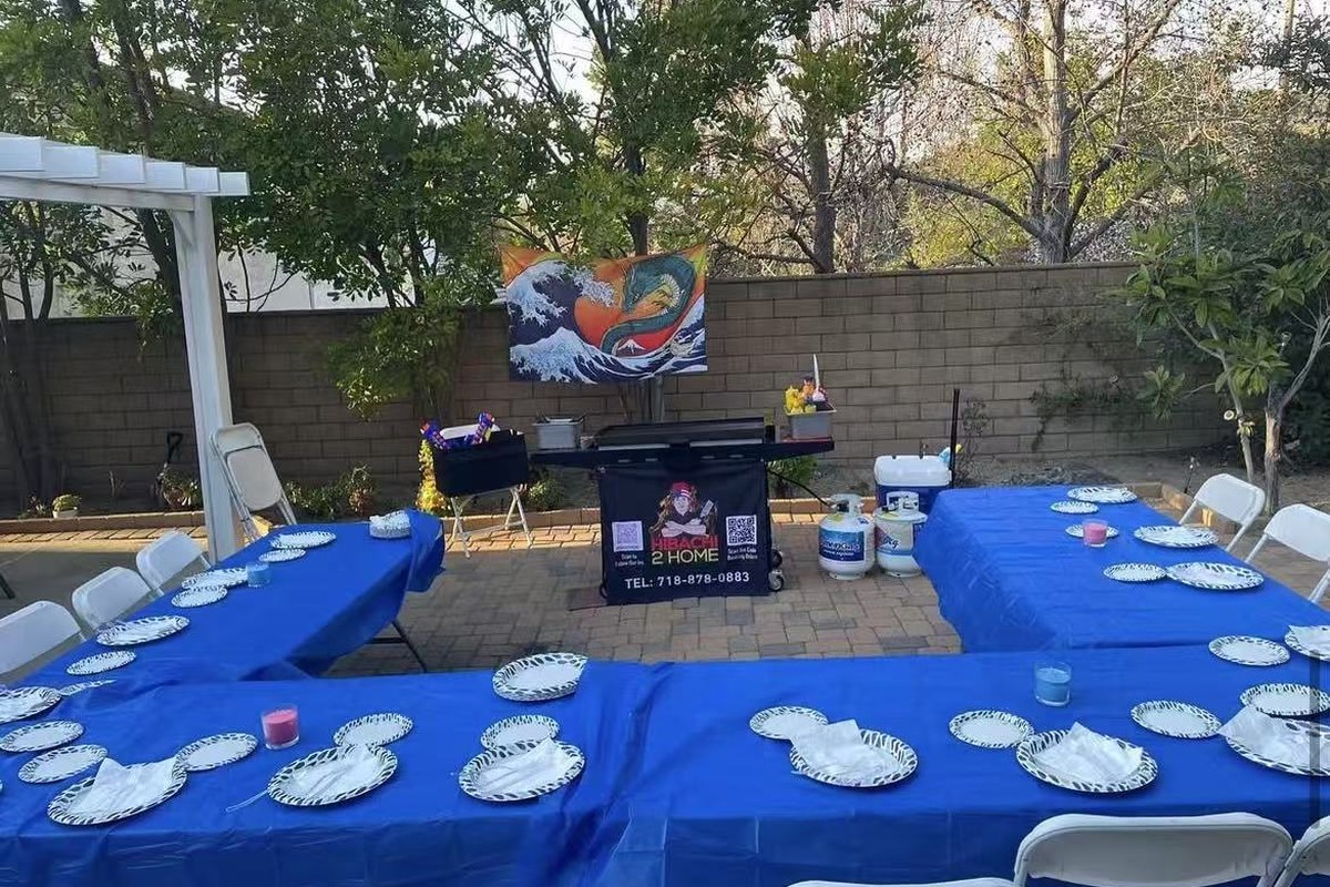 Hibachi 2 Home branded portable grill set up beside guest tables for a private backyard hibachi dinner at home